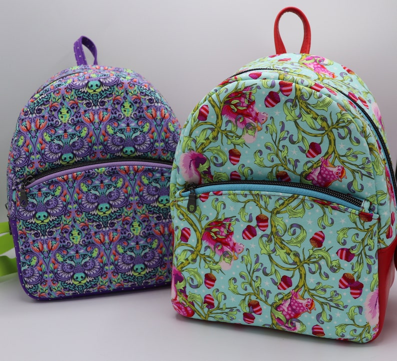Puede incluir: Dos mochilas coloridas con patrones florales y geom&eacute;tricos. La mochila de la izquierda es morada con un patr&oacute;n geom&eacute;trico. La mochila de la derecha es azul con un patr&oacute;n floral.