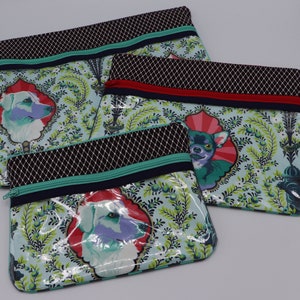 May include: Three zippered pouches with a teal, black, and white geometric pattern. Each pouch features a different animal illustration: a dog, a chihuahua, and another dog. The pouches are lined with clear plastic.
