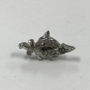 May include: A silver-toned pin with a detailed design of a sword and a crescent moon.