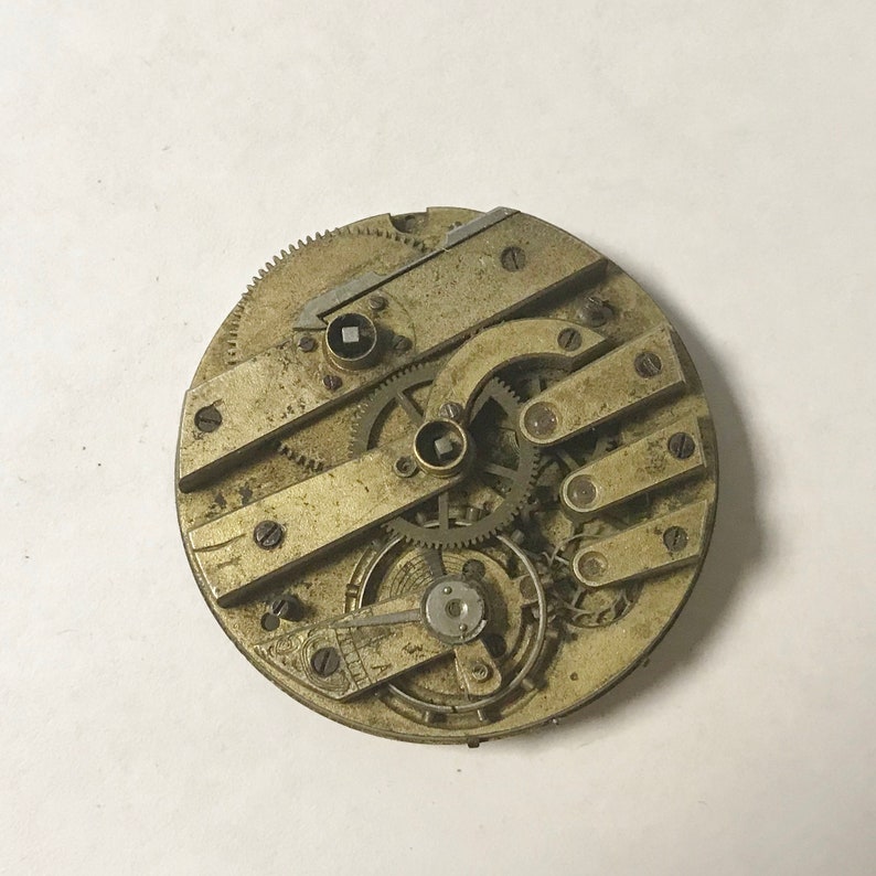 May include: A close-up of a gold-toned pocket watch movement with intricate gears and levers. The watch face is not visible.