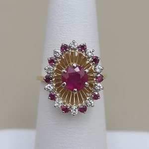 May include: A gold ring with a large red ruby surrounded by smaller rubies and diamonds.