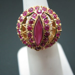 May include: A gold ring with a large, marquise-shaped ruby surrounded by smaller rubies.