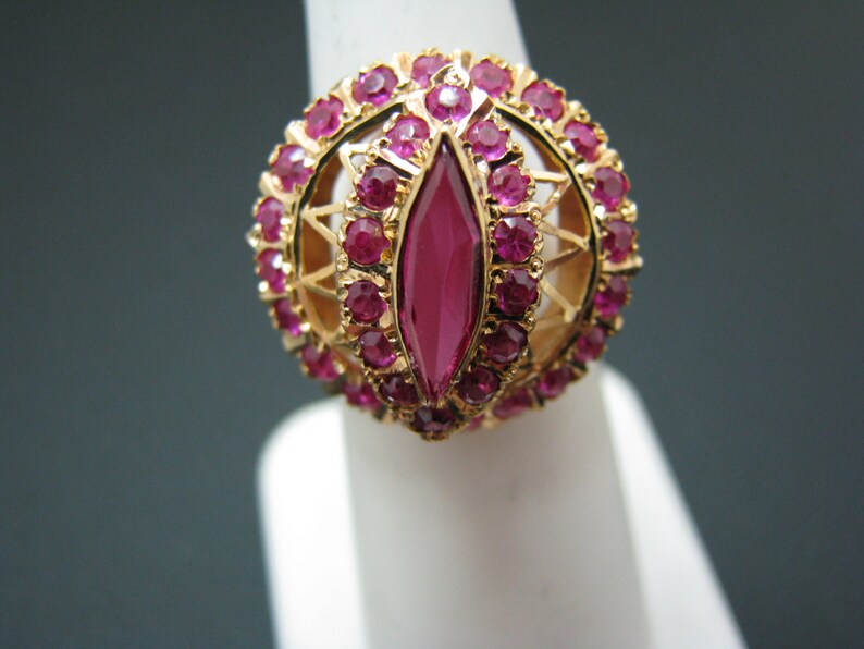 May include: A gold ring with a large, marquise-shaped ruby surrounded by smaller rubies.