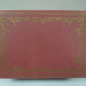 May include: A red box with a gold decorative border. The box has a smooth, leather-like surface.