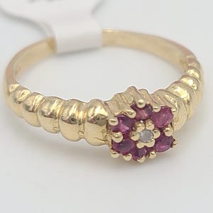 May include: A gold ring with a flower-shaped design set with pink gemstones and a single white gemstone in the center.
