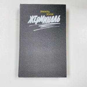 May include: Black hardcover book with the title "Germinal" in white lettering and the author "Emile Zola" in yellow lettering.