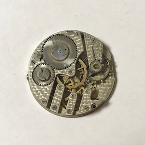May include: A silver watch movement with exposed gears and a patterned back plate.