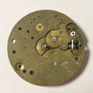 K&ouml;nnte beinhalten: Nahaufnahme eines Messing-Uhrwerks mit komplizierten Zahnr&auml;dern und Hebeln. Das Uhrwerk ist freigelegt und zeigt die inneren Funktionsweisen der Uhr.