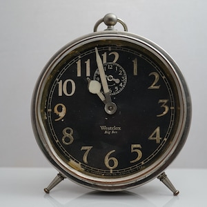 May include: A silver alarm clock with black face and white numbers. The clock is set to 12:00 and reads "Westclox Big Ben".