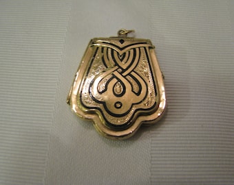 May include: Gold locket with a black enamel design. The locket has a scalloped edge and a loop for a chain.