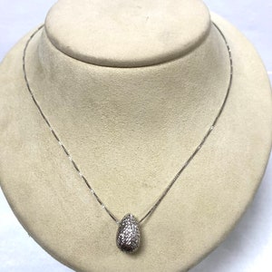 May include: A silver chain necklace with a textured silver egg-shaped pendant.