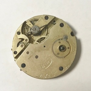 May include: Close-up of a gold-toned pocket watch movement with the inscription "L.B. & S.  Great  London  No. 220910".