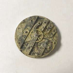 May include: Close-up of a vintage pocket watch movement with intricate gears and levers. The metal is aged and has a worn patina.