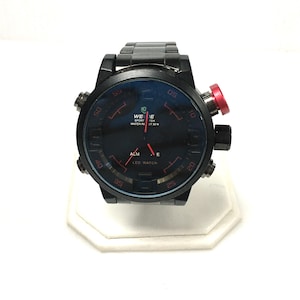 May include: Black LED sport watch with a round face and a black band. The watch face has red accents and the text "WEDE SPORT TCH WATER REST 30 M". The watch has a red button on the side.