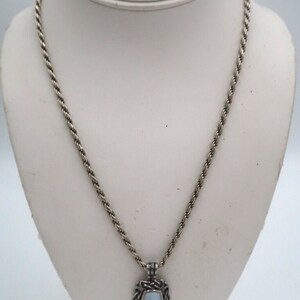 May include: A silver chain necklace with a silver pendant featuring a light blue oval-shaped stone set in a decorative frame.