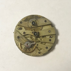 May include: Close-up of a vintage pocket watch movement with intricate gears and a brass finish.