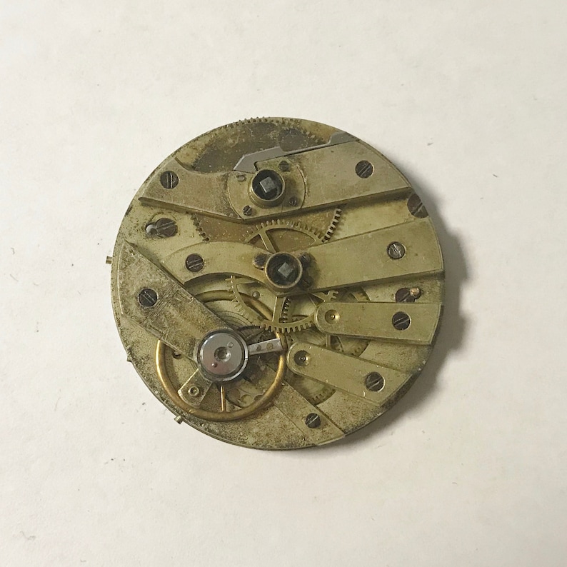 May include: Close-up of a vintage pocket watch movement with intricate gears and a brass finish.