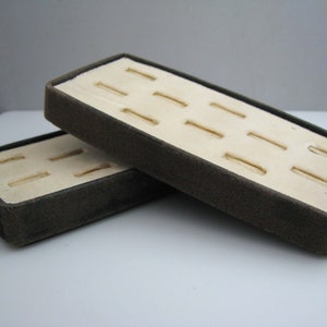 May include: Two brown ring display boxes with white velvet lining and multiple slots for rings.