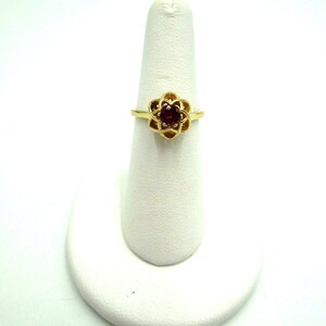 May include: A gold ring with a red gemstone set in a flower design.