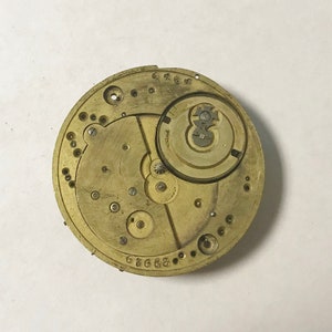 May include: Close-up of a gold-toned watch movement with intricate gears and markings. The movement is labeled "676683".