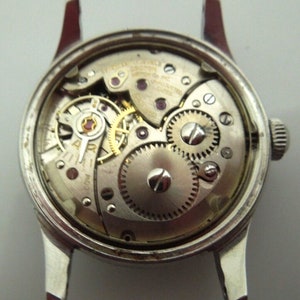 May include: A silver watch with a clear back showing the inner workings of the watch mechanism.