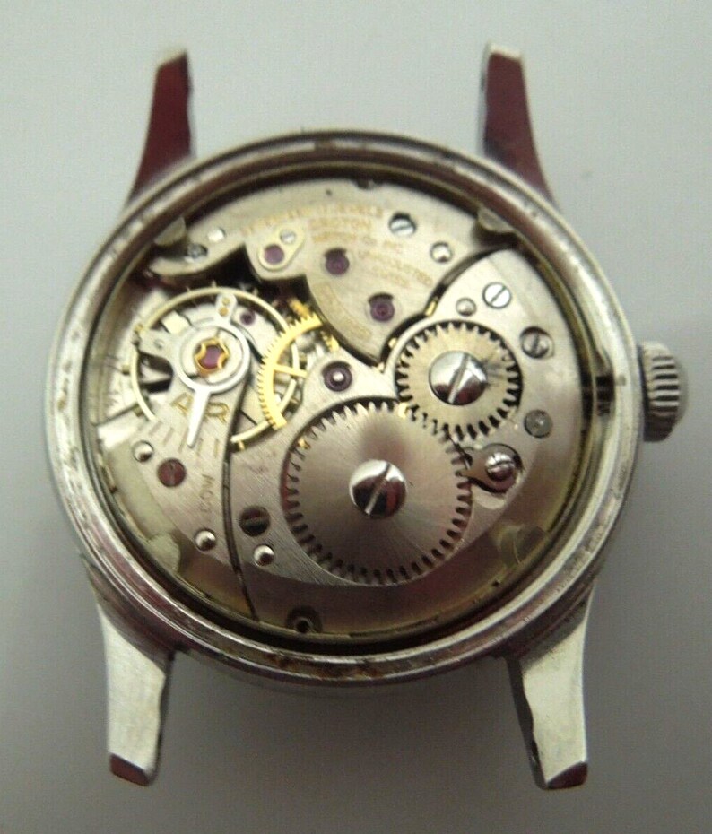 May include: A silver watch with a clear back showing the inner workings of the watch mechanism.