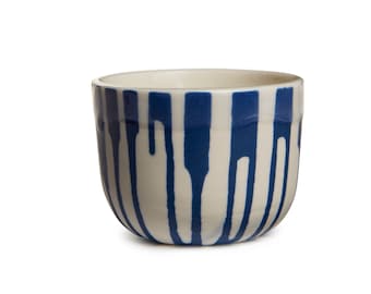 May include: A white ceramic bowl with blue vertical stripes. The stripes are uneven and have a drip effect.