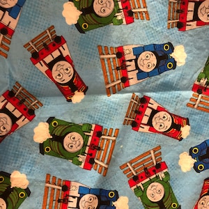 May include: A blue background with a repeating pattern of cartoon trains. The trains are red, green, and blue with black wheels and white smoke. The trains have faces and are smiling.