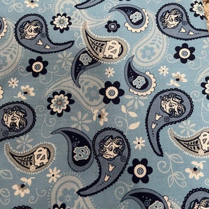 May include: Blue paisley fabric with a white and gray floral pattern. The fabric features a repeated design of a ram's head with the letters "UNC" above it.