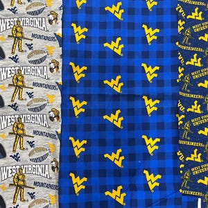 May include: Fabric swatches featuring West Virginia University Mountaineers logos and graphics. Designs include a gray background with team logos, a blue plaid pattern with yellow WV logos, and a navy blue pattern with WVU text and logos.