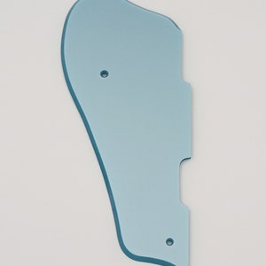 May include: A light blue plastic guitar pickguard with two small holes.