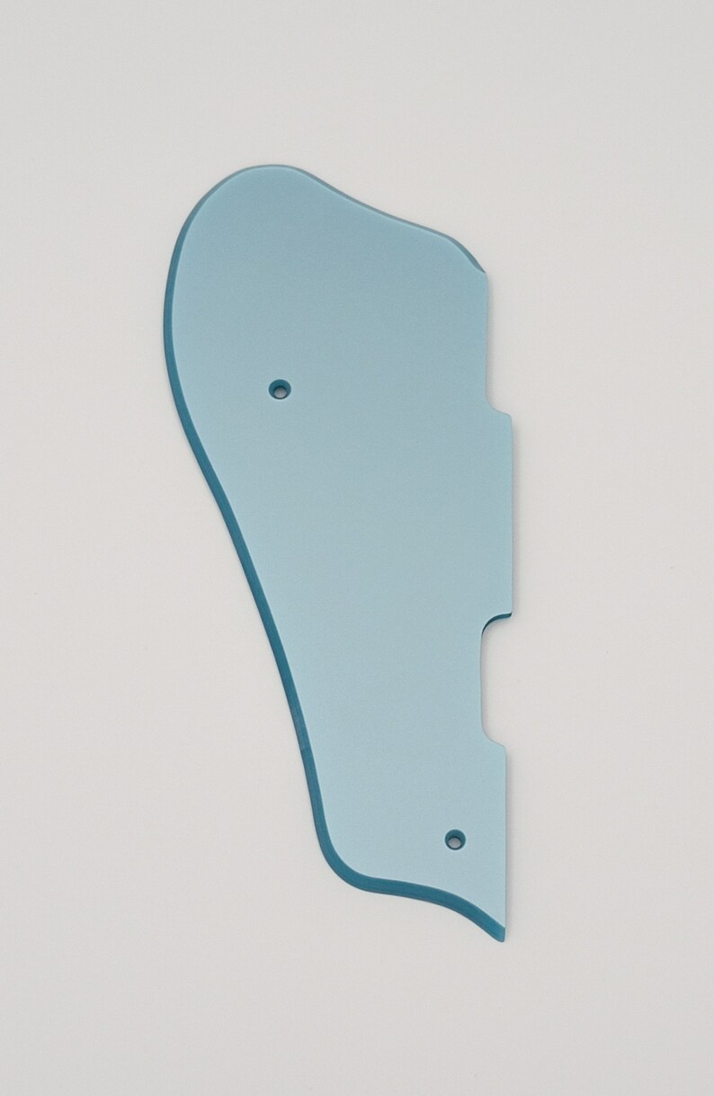 May include: A light blue plastic guitar pickguard with two small holes.