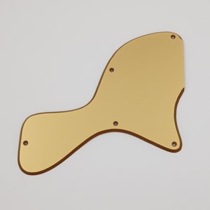Pode incluir: Golpeador de guitarra dourado com bordas arredondadas e vários pequenos furos.