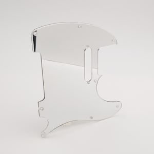 Könnte beinhalten: Klarer Kunststoff-Pickguard für eine E-Gitarre. Der Pickguard hat eine abgerundete Oberseite und einen Ausschnitt für den Tonabnehmer der Gitarre.