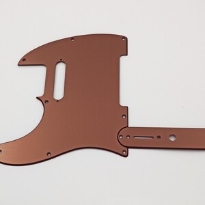 Op de afbeelding: Een koperkleurige gitaar pickguard met een enkele cutaway en een controleplaat. De pickguard is gemaakt van metaal en heeft een gladde, glanzende afwerking.