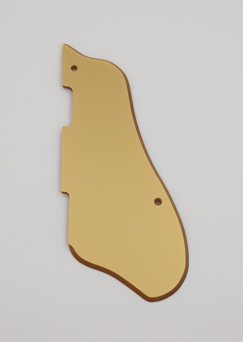 May include: Gold-colored guitar pickguard with rounded edges and two small holes.