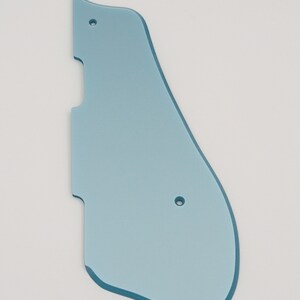 May include: A light blue plastic guitar pickguard with two small holes.