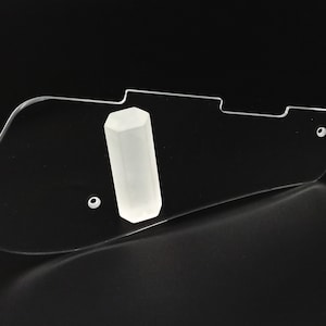 Puede incluir: Un protector de guitarra de pl&aacute;stico transparente con un soporte de p&uacute;a hexagonal blanco.