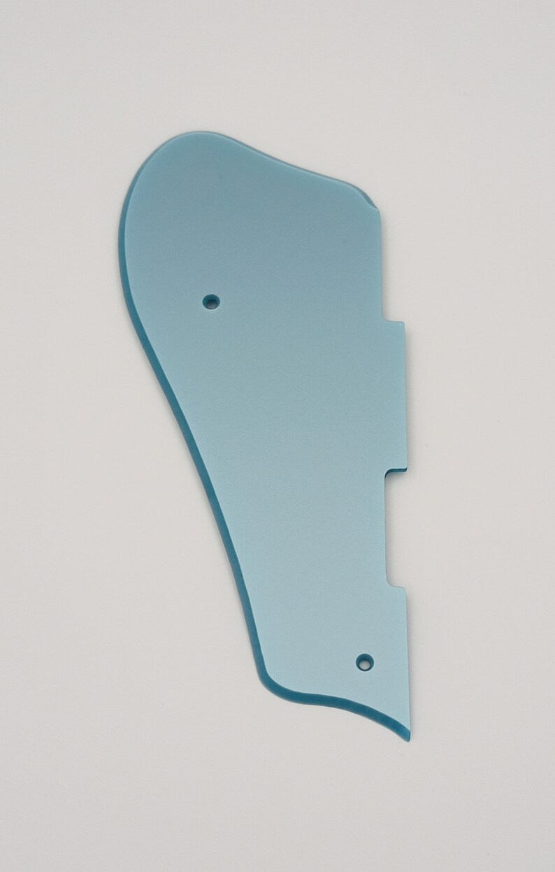 May include: A light blue plastic guitar pickguard with three holes.