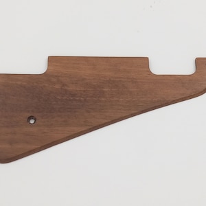 Peut inclure: Un pickguard de guitare en bois brun avec deux trous.
