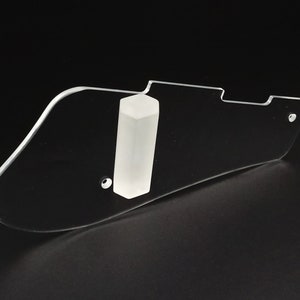 Puede incluir: Un pickguard de guitarra de pl&aacute;stico transparente con un anillo de montaje de pickguard de pl&aacute;stico blanco. El pickguard tiene una forma redondeada y un agujero para un tornillo.