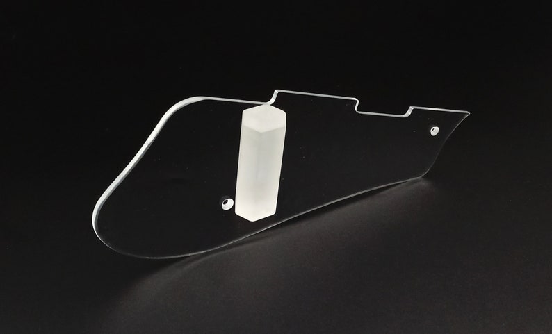 Puede incluir: Un pickguard de guitarra de pl&aacute;stico transparente con un anillo de montaje de pickguard de pl&aacute;stico blanco. El pickguard tiene una forma redondeada y un agujero para un tornillo.