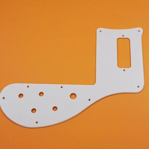 May include: White plastic guitar pickguard with multiple round holes and a rectangular cutout for a pickup.
