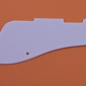 May include: A white plastic guitar pickguard with rounded edges and two small holes.