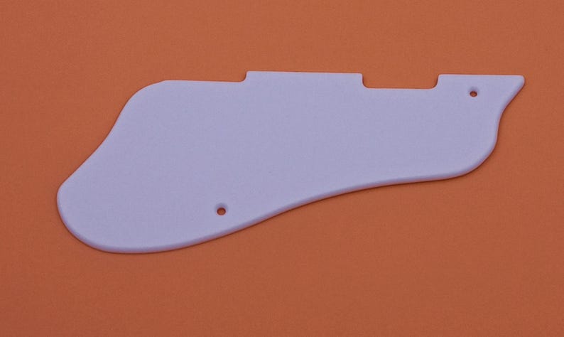 May include: A white plastic guitar pickguard with rounded edges and two small holes.