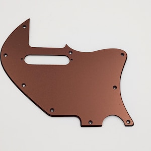 May include: A copper-colored guitar pickguard with multiple screw holes and a cutout for a pickup.