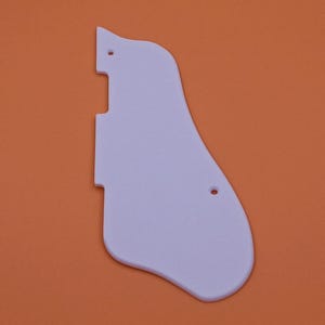 May include: White plastic guitar pickguard with two small holes.