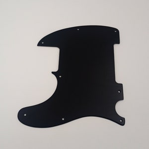 Może przedstawiać: Czarny pickguard do gitary z wieloma otworami na śruby.