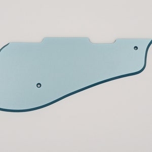 May include: A light blue plastic guitar pickguard with two small holes.
