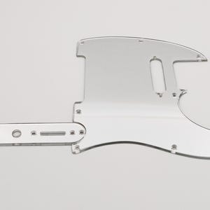 Könnte beinhalten: Ein durchsichtiger Gitarren-Pickguard aus Kunststoff mit einer Aussparung für einen Single-Coil-Pickup und eine Kontrollplatte. Der Pickguard ist für eine E-Gitarre im Fender-Stil konzipiert.